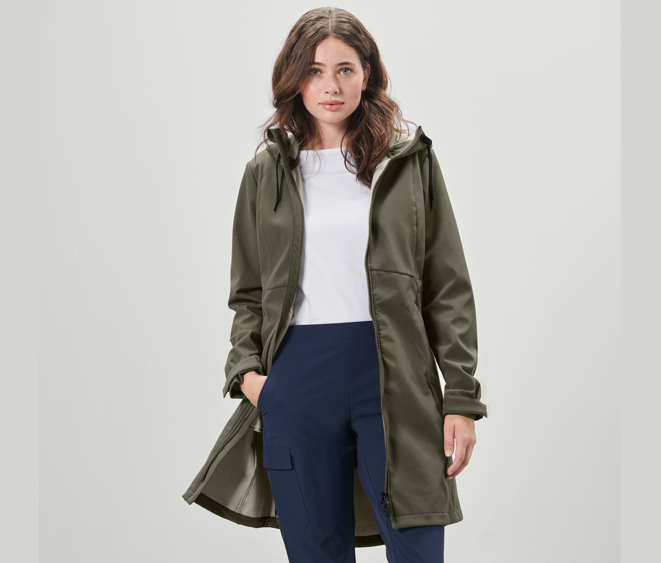 Žena má na sobě khaki softshellový kabát.
