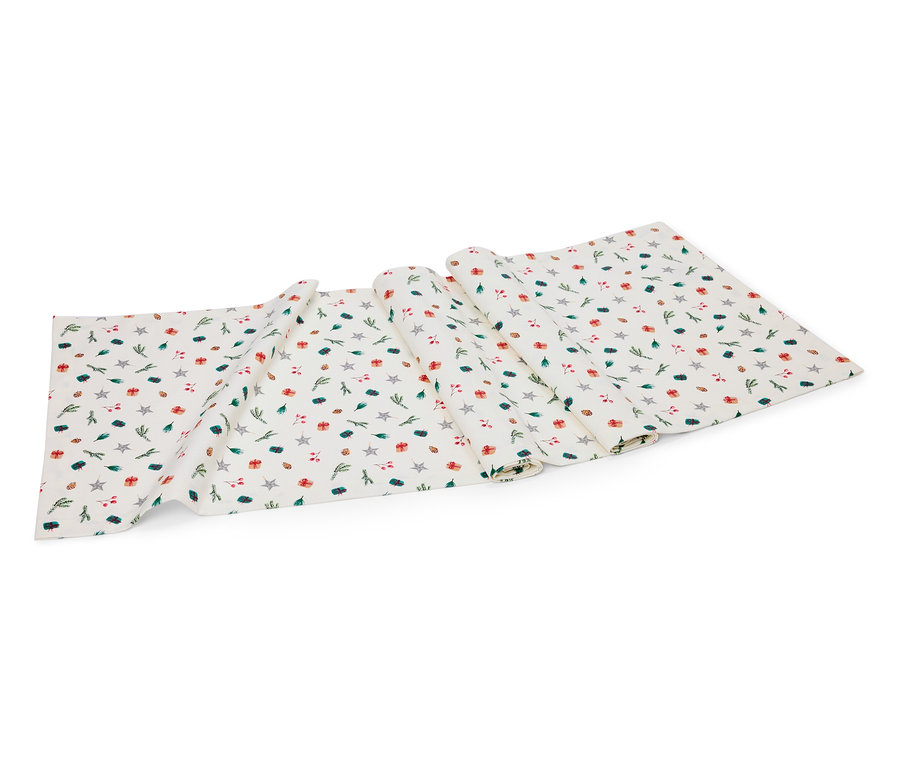 Bílý ubrus se vzorem hvězd, dárků a větviček.