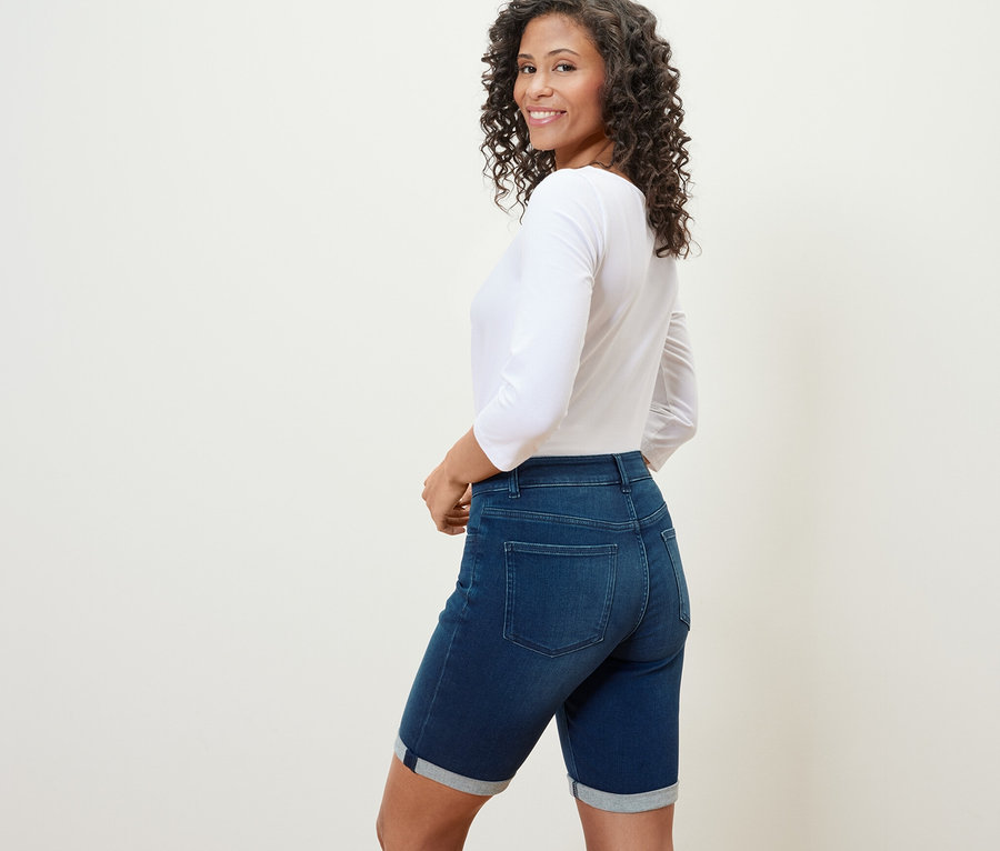 Žena se dívá přes rameno a má na sobě džínové bermudy »Lea« tmavě modré barvy.