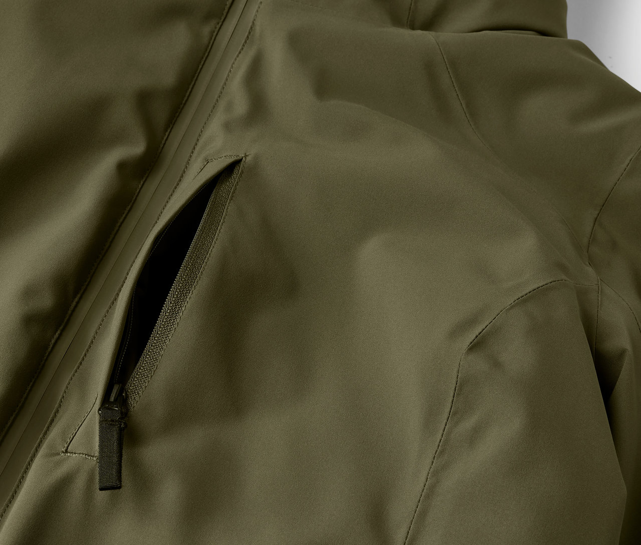 Detail olivově zelené bundy s kapsou na zip.