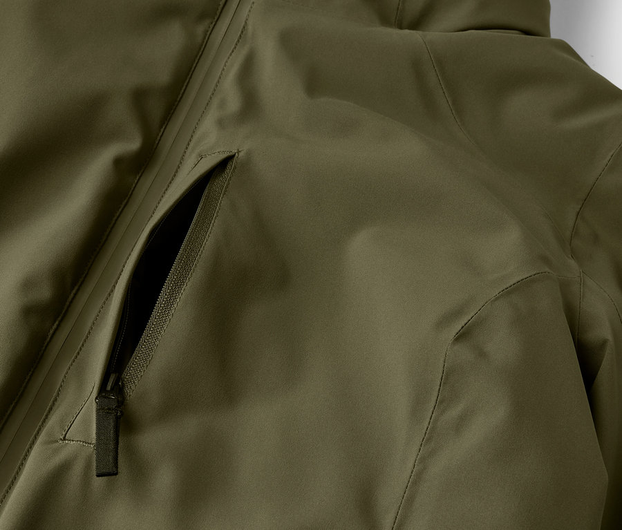 Detail olivově zelené bundy s kapsou na zip.