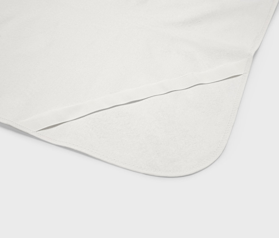 Detailní záběr na bílou dětskou deku se zaoblenými rohy a elastickým lemem.