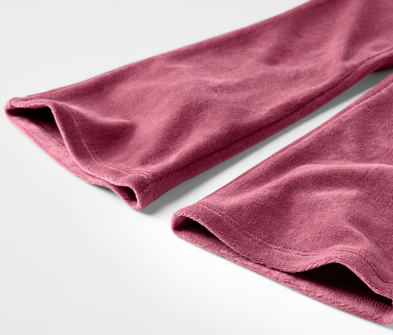 Detail bordó sametových kalhot na bílém pozadí.