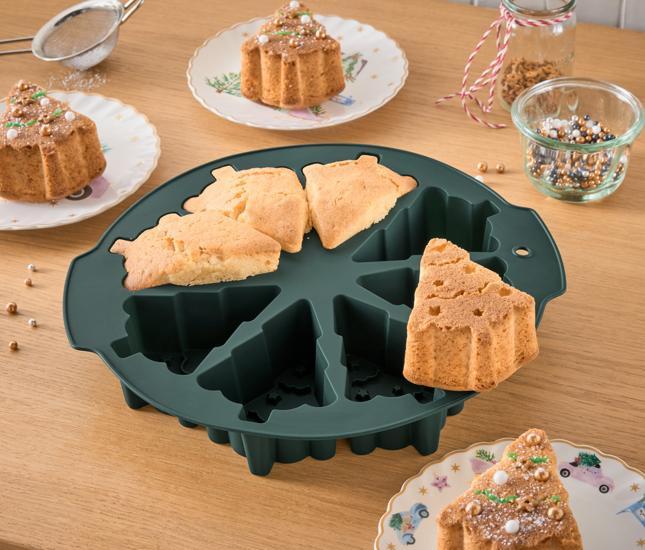 Forma na pečení ve tvaru vánočního stromku s upečenými bábovkami a zdobené bábovky na talířích.