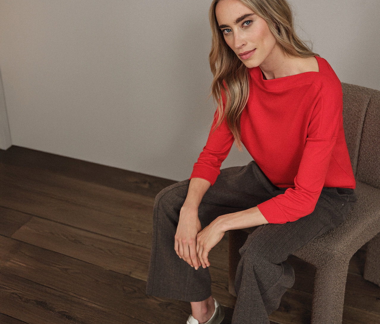 Žena sedí na židli a má na sobě červené tričko Street One s žebrovaným detailem.