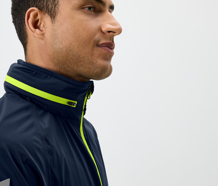 Profil muže v tmavě modré bundě se žlutými detaily.