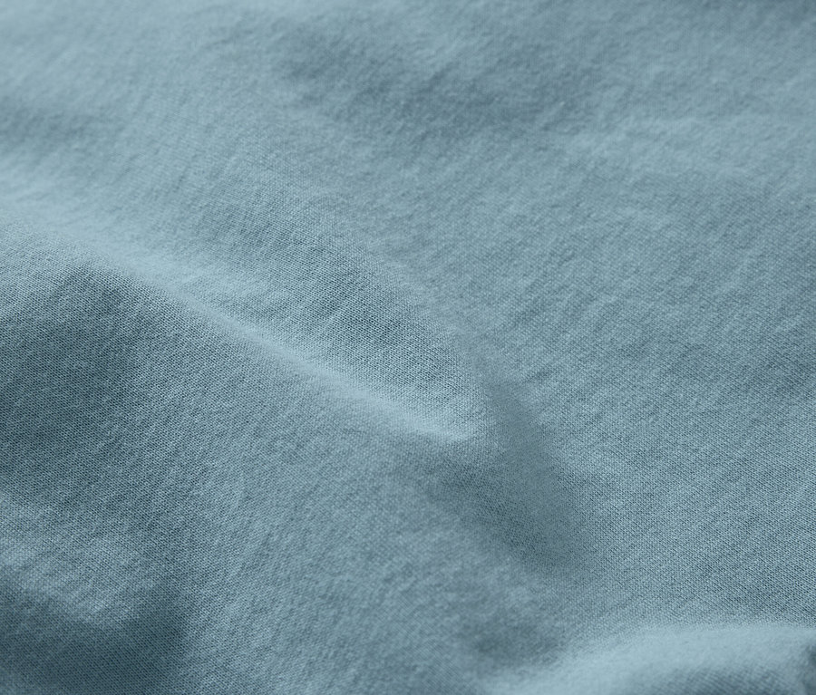 Detailní záběr na světle modrou látku s jemnou texturou a záhyby.