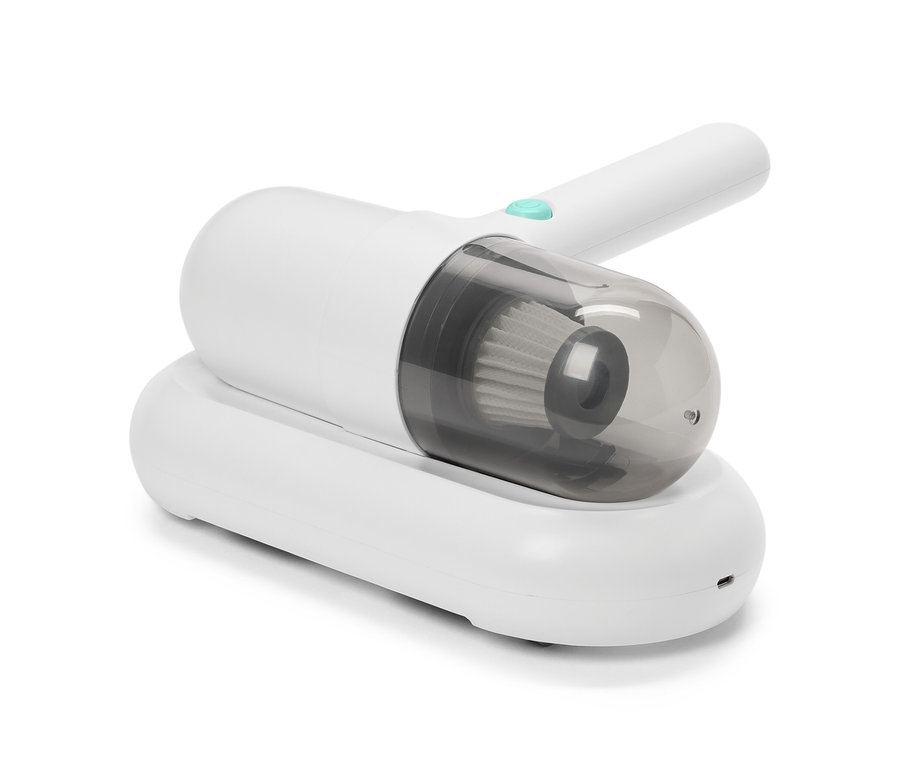 Bílý vysavač na roztoče na bílém nabíjecím stojanu.