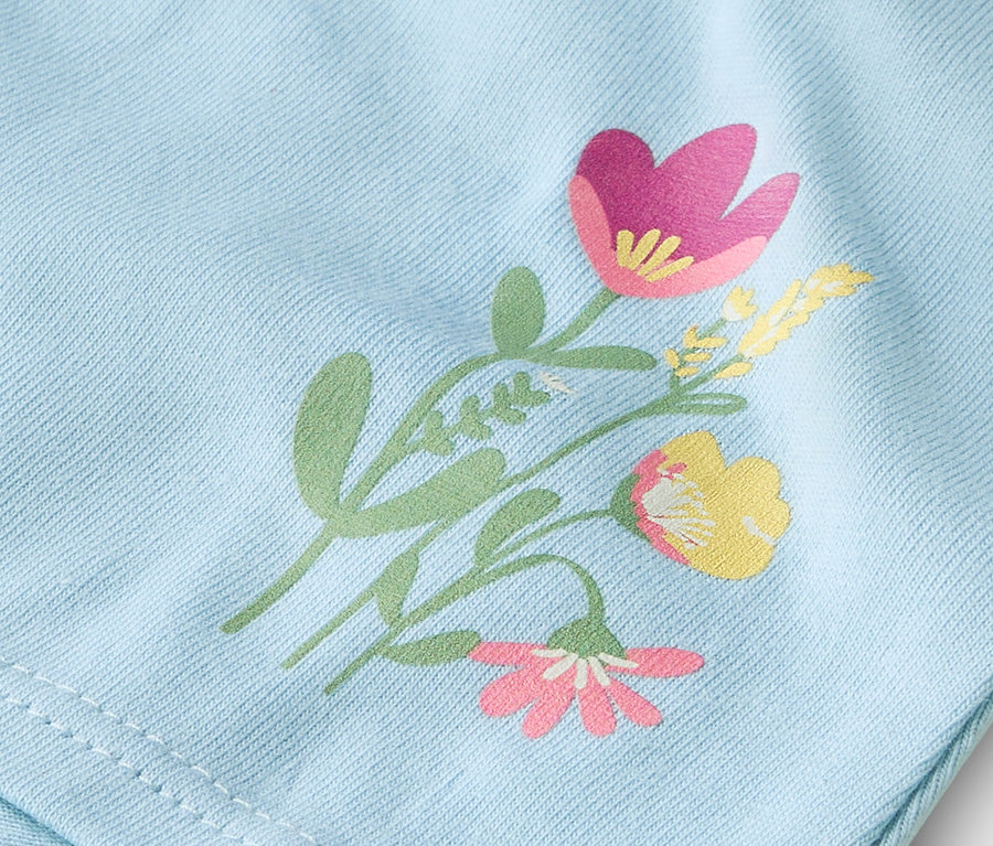 Detailní záběr na světle modrou látku s tištěným květinovým vzorem.