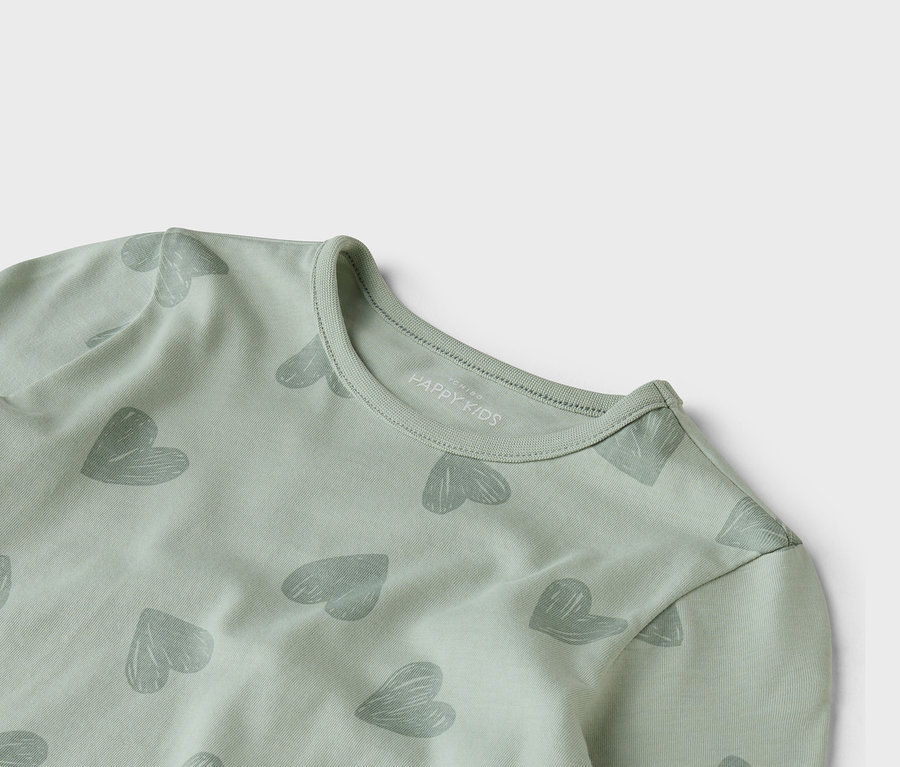 Detailní záběr světle zeleného trička s dlouhým rukávem se šedým vzorem srdce.