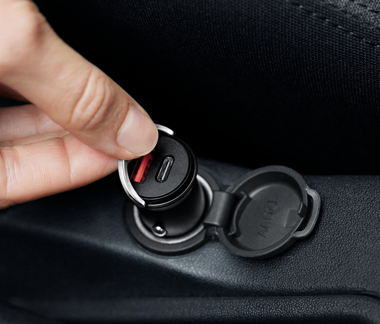 Ruka připojuje černou nabíječku do auta USB-C.