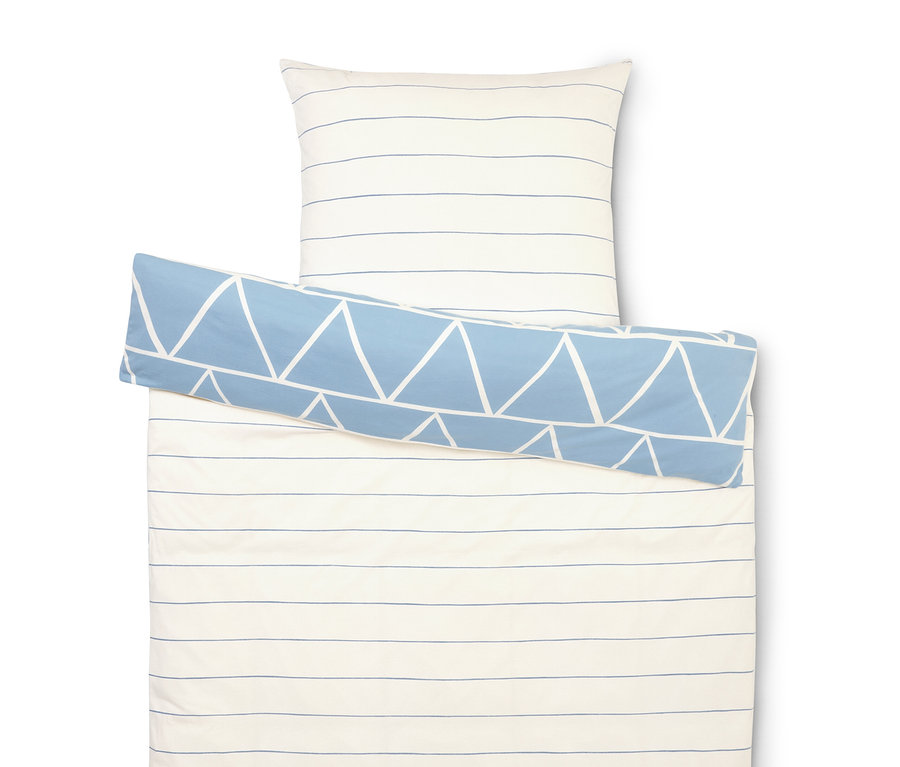 Sada ložního prádla s bílými a modrými pruhy, povlak na polštář a modrý váleček s bílými trojúhelníky.