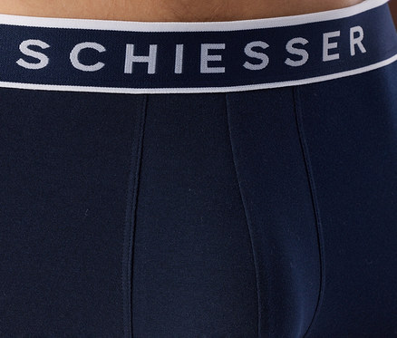 Detail tmavě modrých spodních kalhot s bílým pasem. Na pase je tmavě modrý nápis „SCHIESSER“.