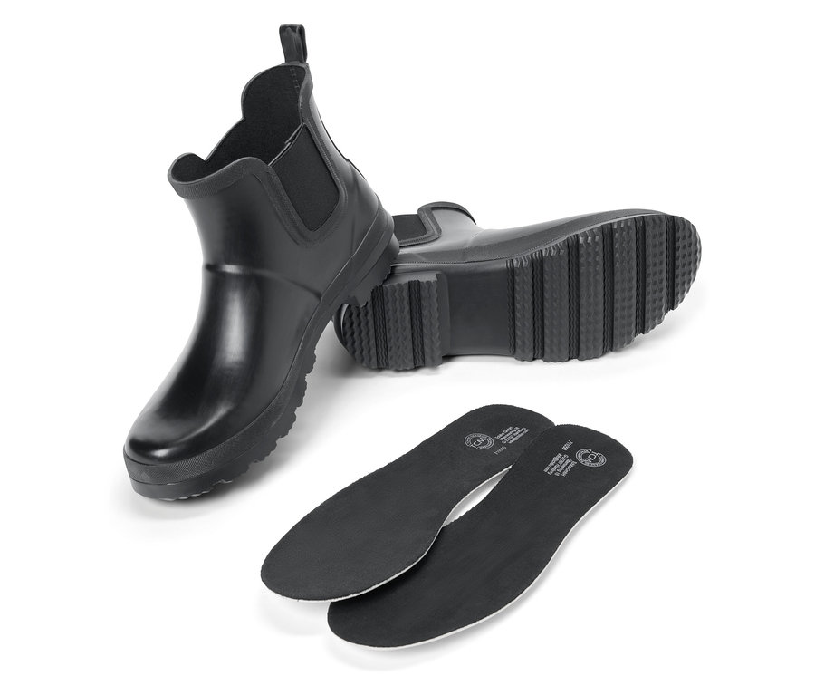 Dva černé gumové boty a dvě černé vložky do bot na bílém pozadí.