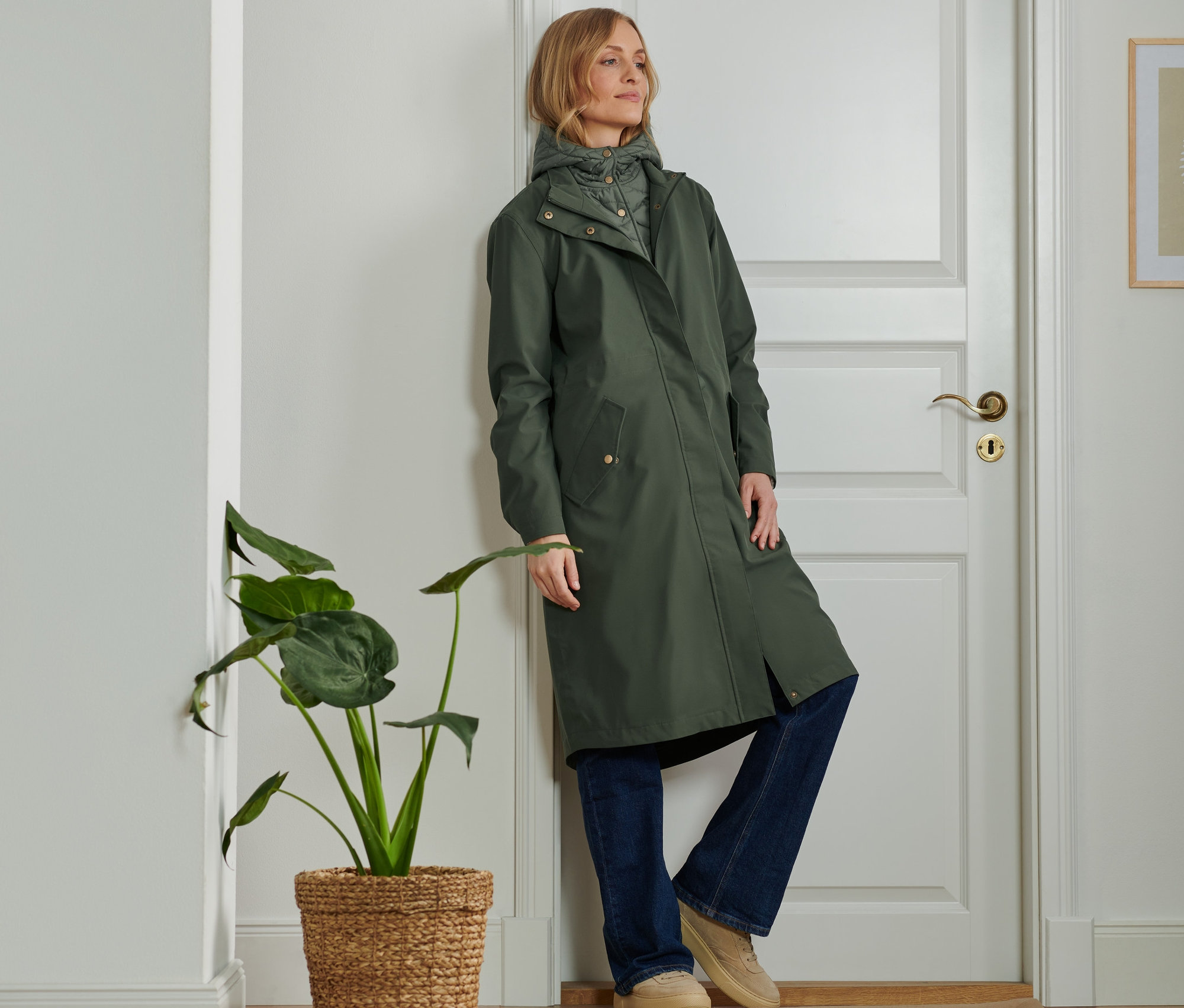 Žena opřená o dveře má na sobě outdoorovou parku 2 v 1.