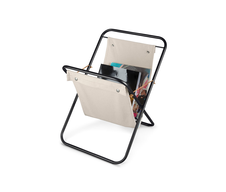 Černý kovový stojan na časopisy s béžovou látkou.