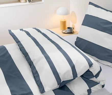 Detail perkálového povlečení s proužky standardní velikosti na posteli.