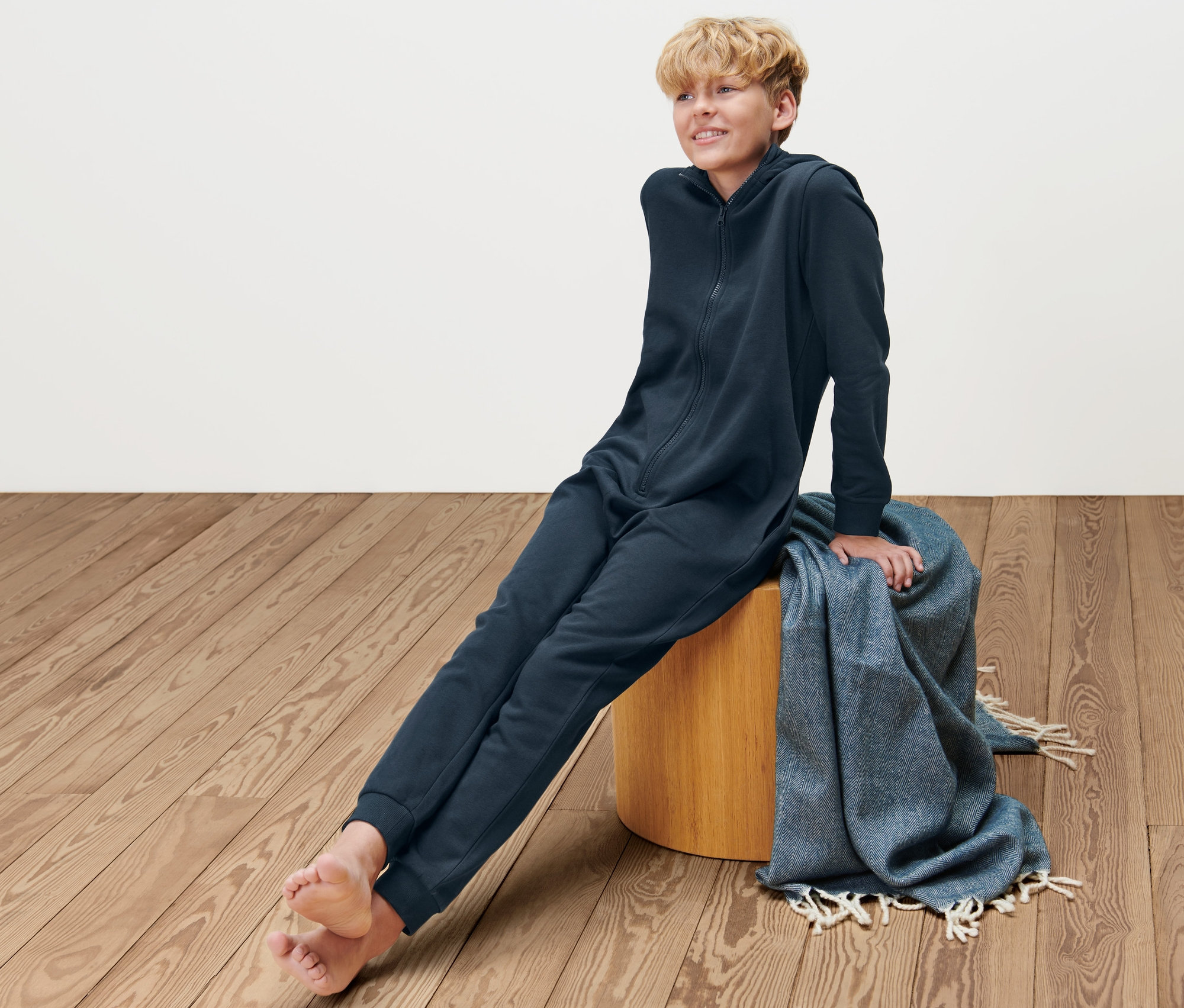 Chlapec sedí na stoličce a má na sobě tmavě modrý dětský pohodlný overal.
