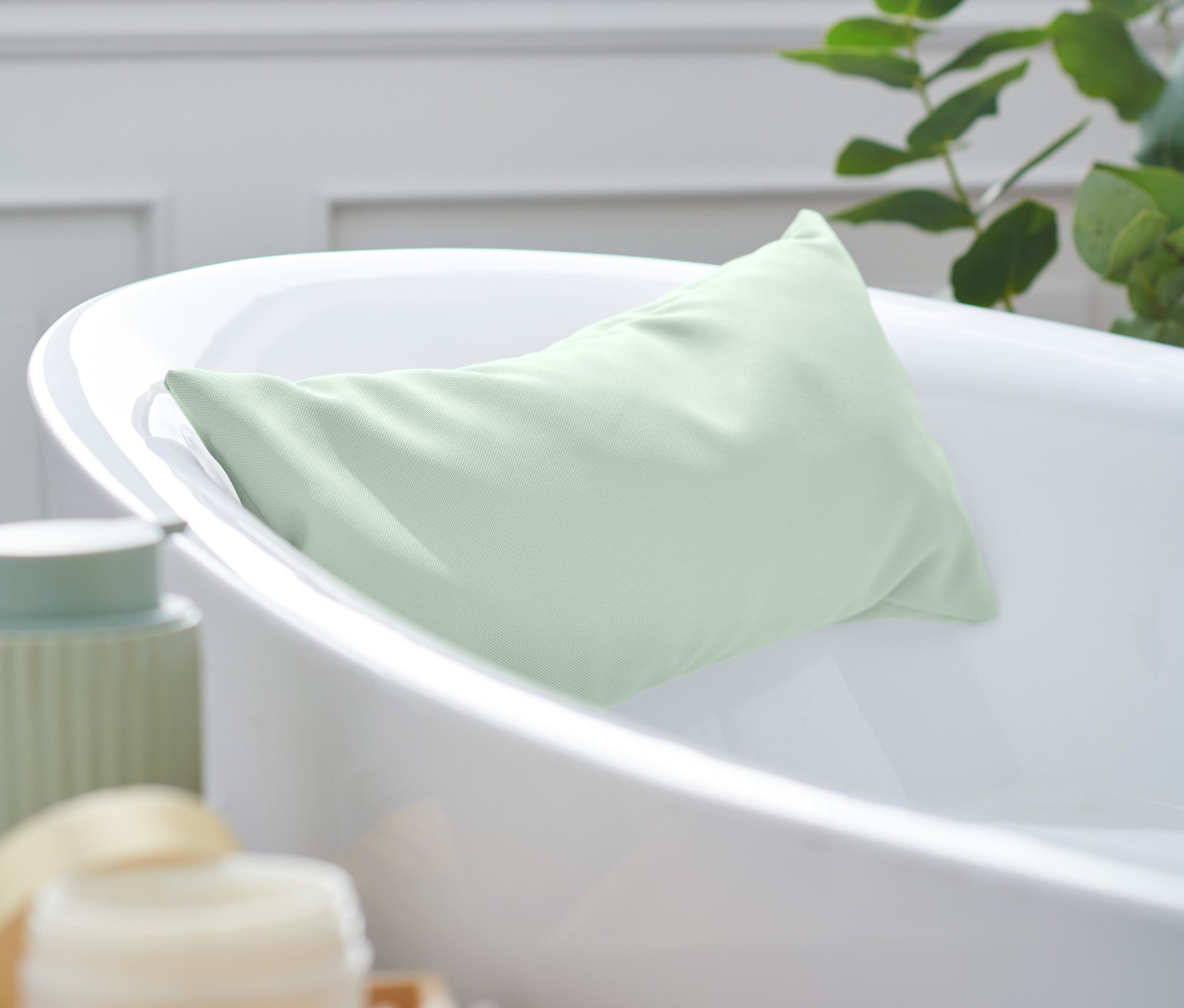 Zelený polštářek do vany leží v bílé vaně.