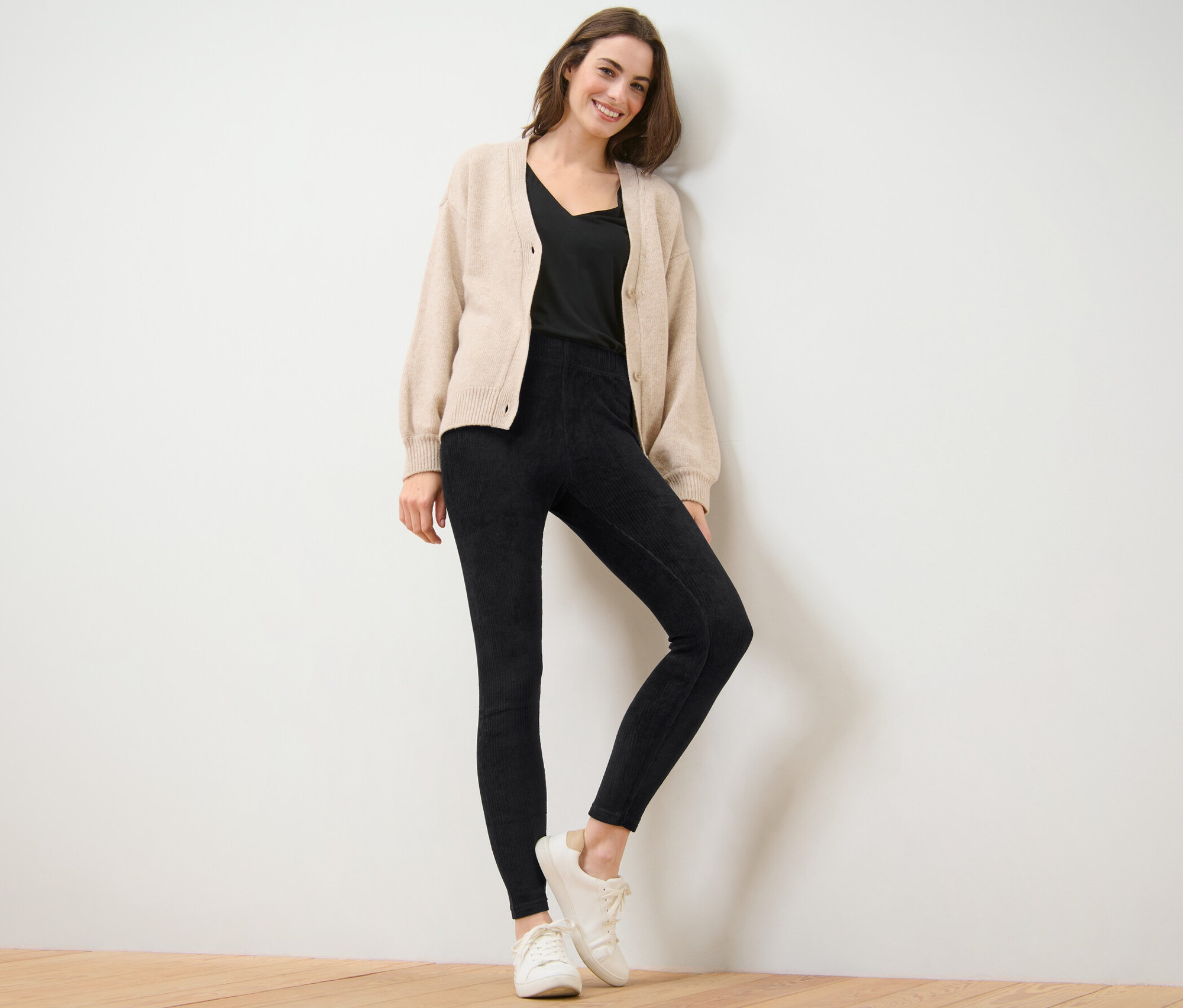 Žena pózuje v černých manšestrových legínách.