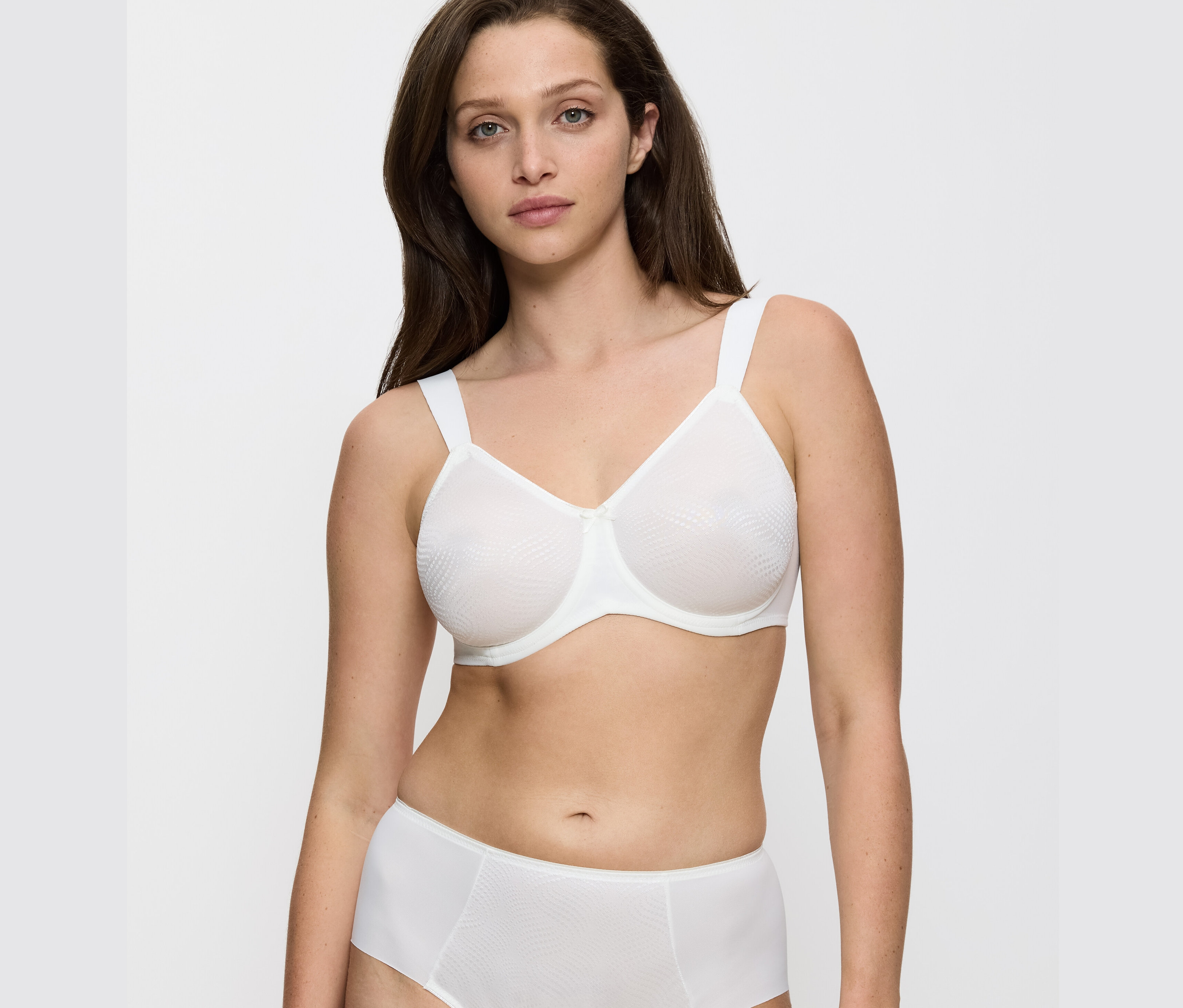 Žena má na sobě vanilkovou podprsenku Triumph Essential »Minimizer W X« a kalhotky.