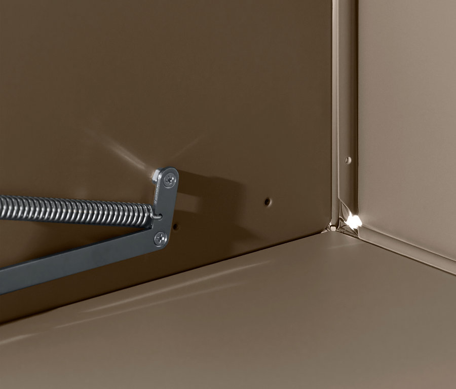 Detail interiéru skříně s mechanismem pružiny na stěně.