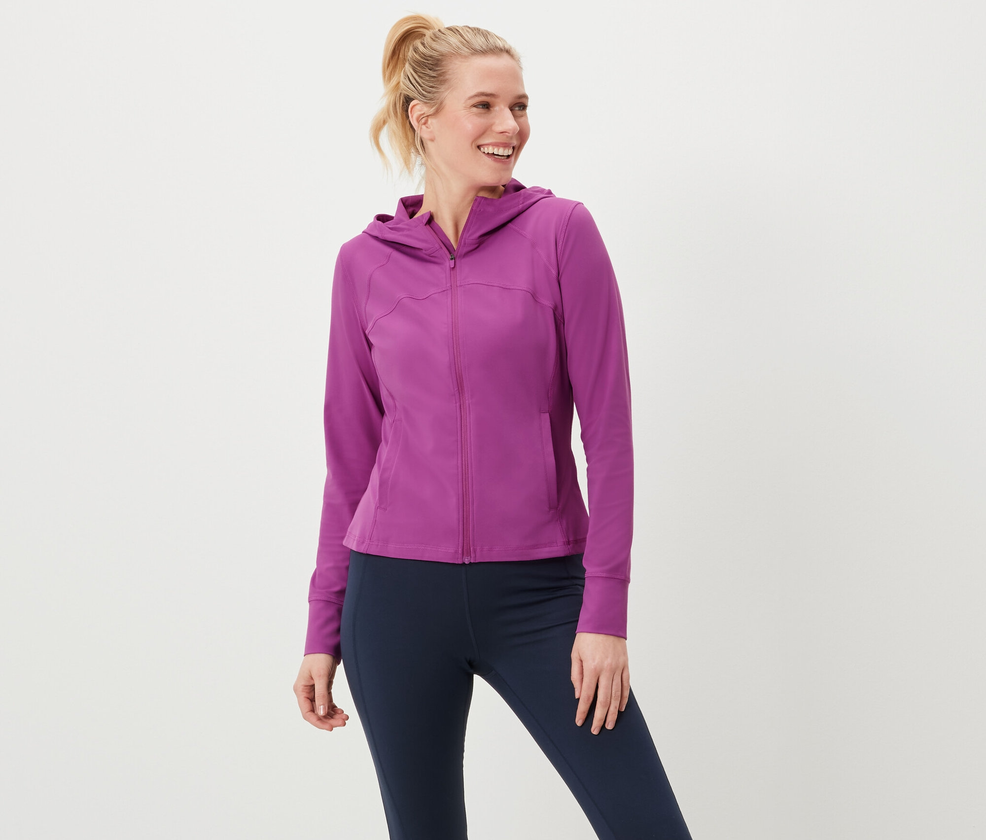 Žena má na sobě sportovní bundu a legíny.