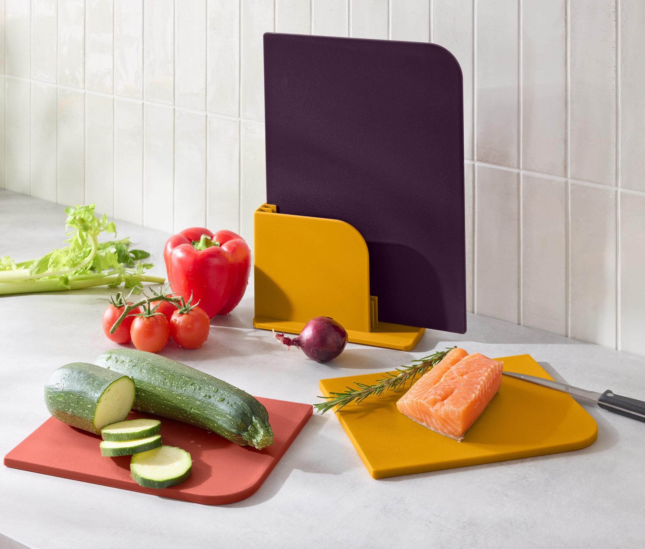 Zelenina a losos na barevných prkénkách na krájení.