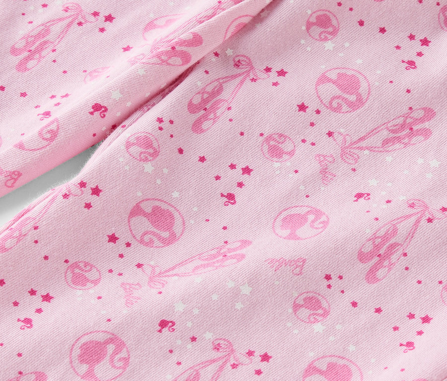 Detail růžové látky s potiskem baletek, hvězd a siluet Barbie.