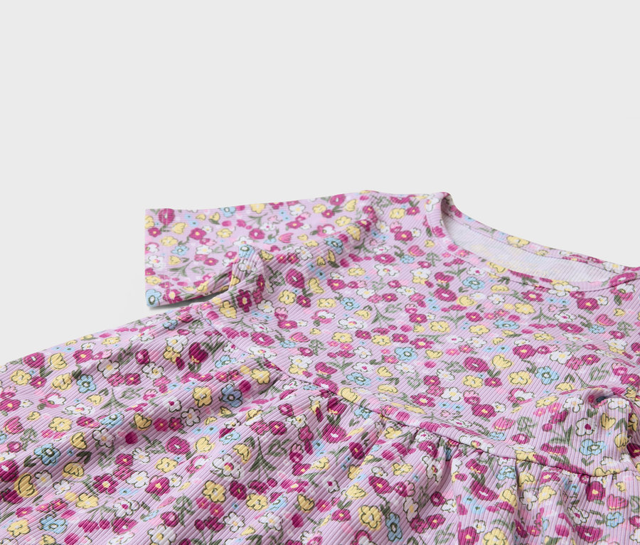 Detail fialových šatů s květinovým potiskem.