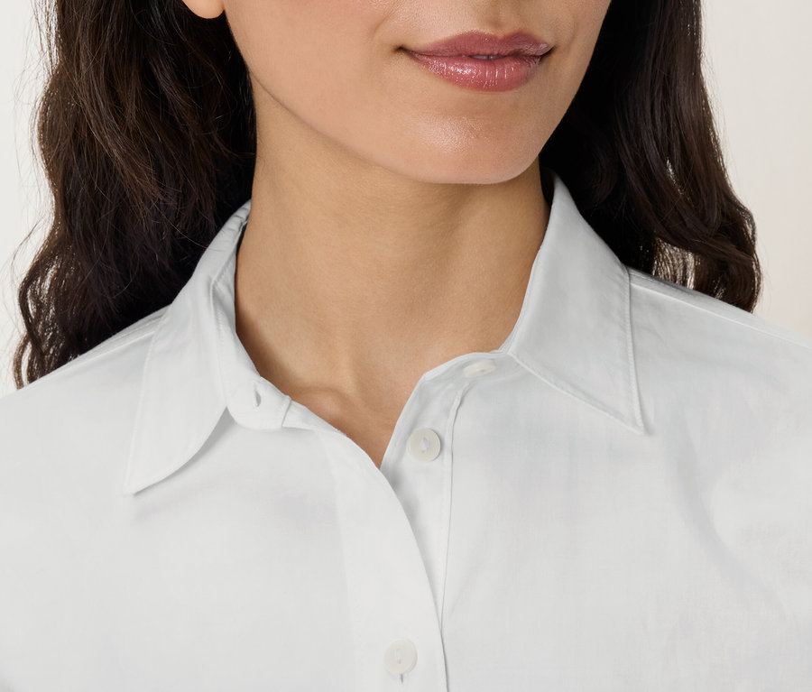 Detail obličeje a horní části těla ženy v bílé košili s límečkem.