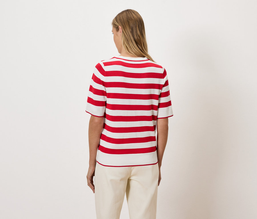 Žena zády k fotoaparátu má na sobě červeno-bílý pruhovaný top.