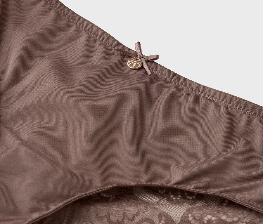 Detailní záběr na hnědé spodní prádlo s krajkovým lemem a mašlí.