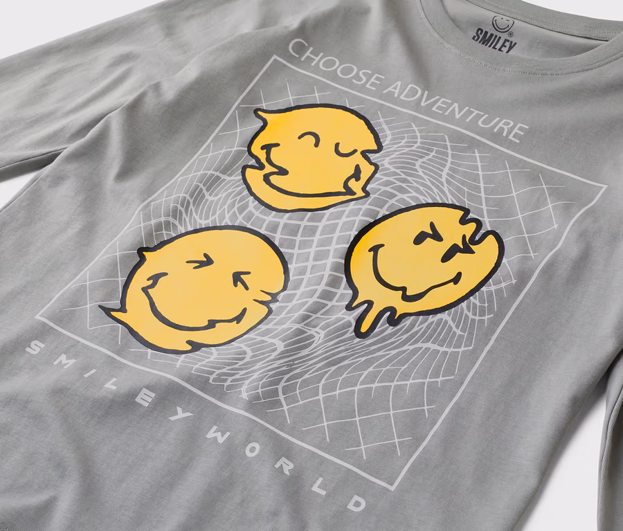 Šedé tričko s dlouhým rukávem se třemi žlutými smajlíky a nápisem „Choose Adventure“ a „Smiley World“.