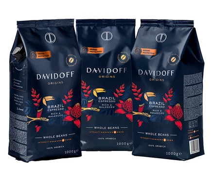 Tři balení zrnkové kávy Davidoff Origins Brazil Espresso, každé balení je tmavě modré s červenými květinami a žlutými ptáky.