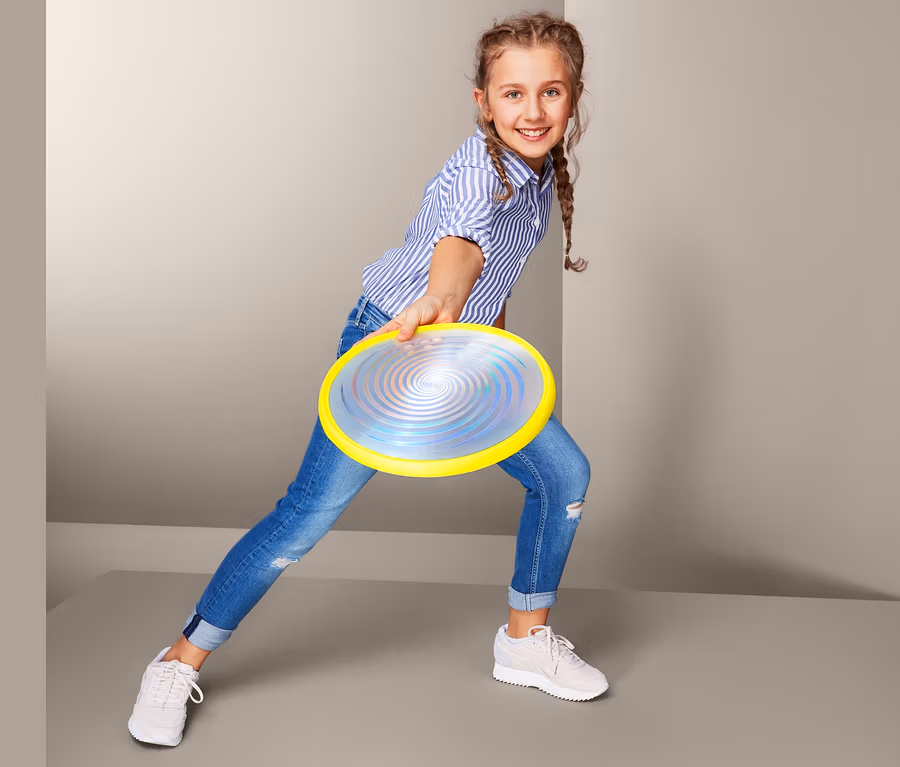 Dívka hází létající talíř s LED světlem.