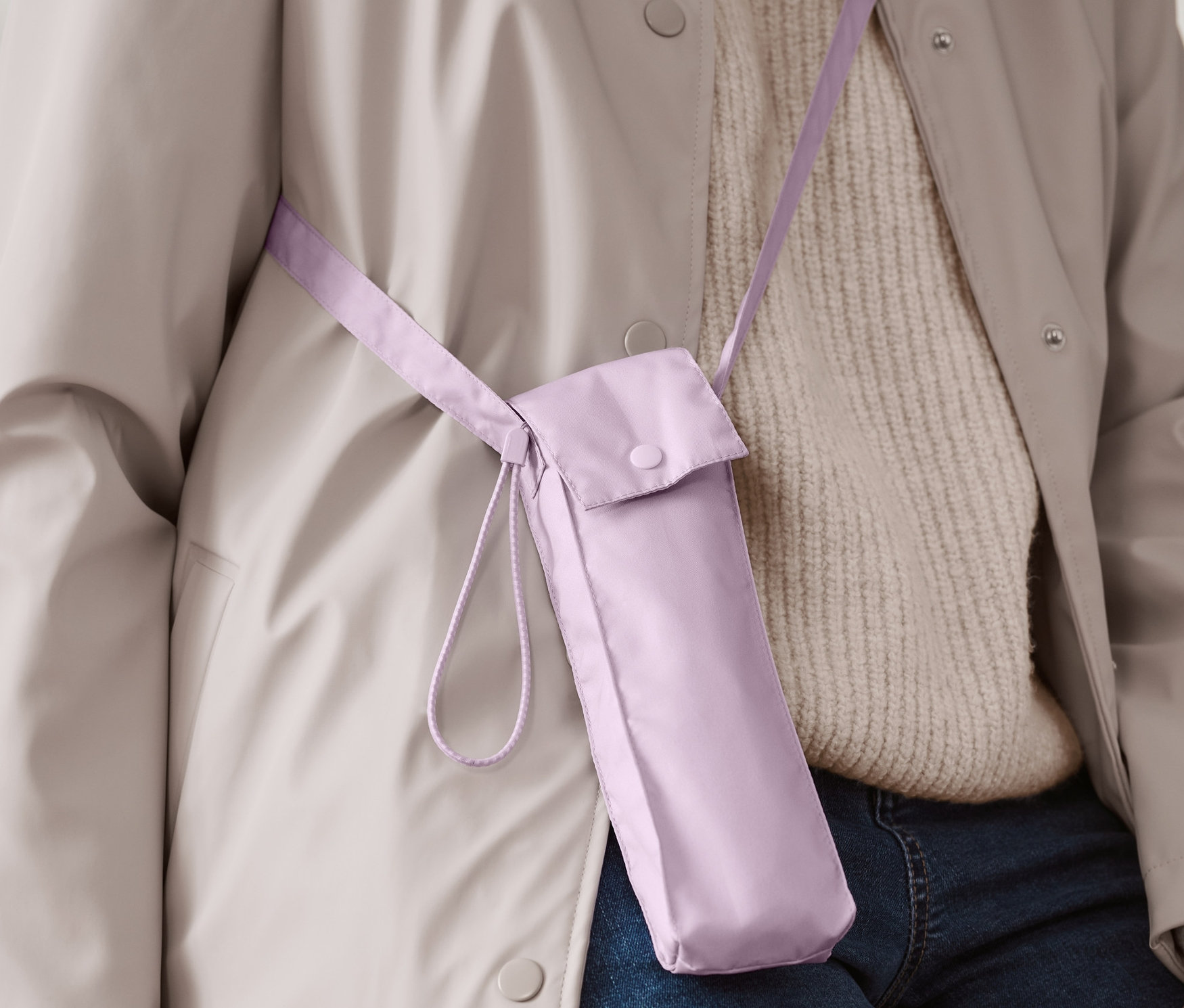 Osoba má na sobě pouzdro se skládacím deštníkem světle fialové barvy přes rameno.