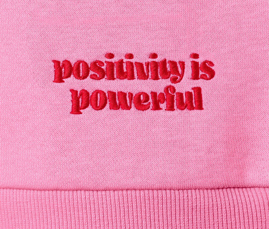 Detail růžové mikiny s červeným nápisem "positivity is powerful".