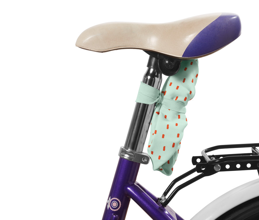 Dětský potah na kolo s červenými tečkami připevněný k sedlu kola.