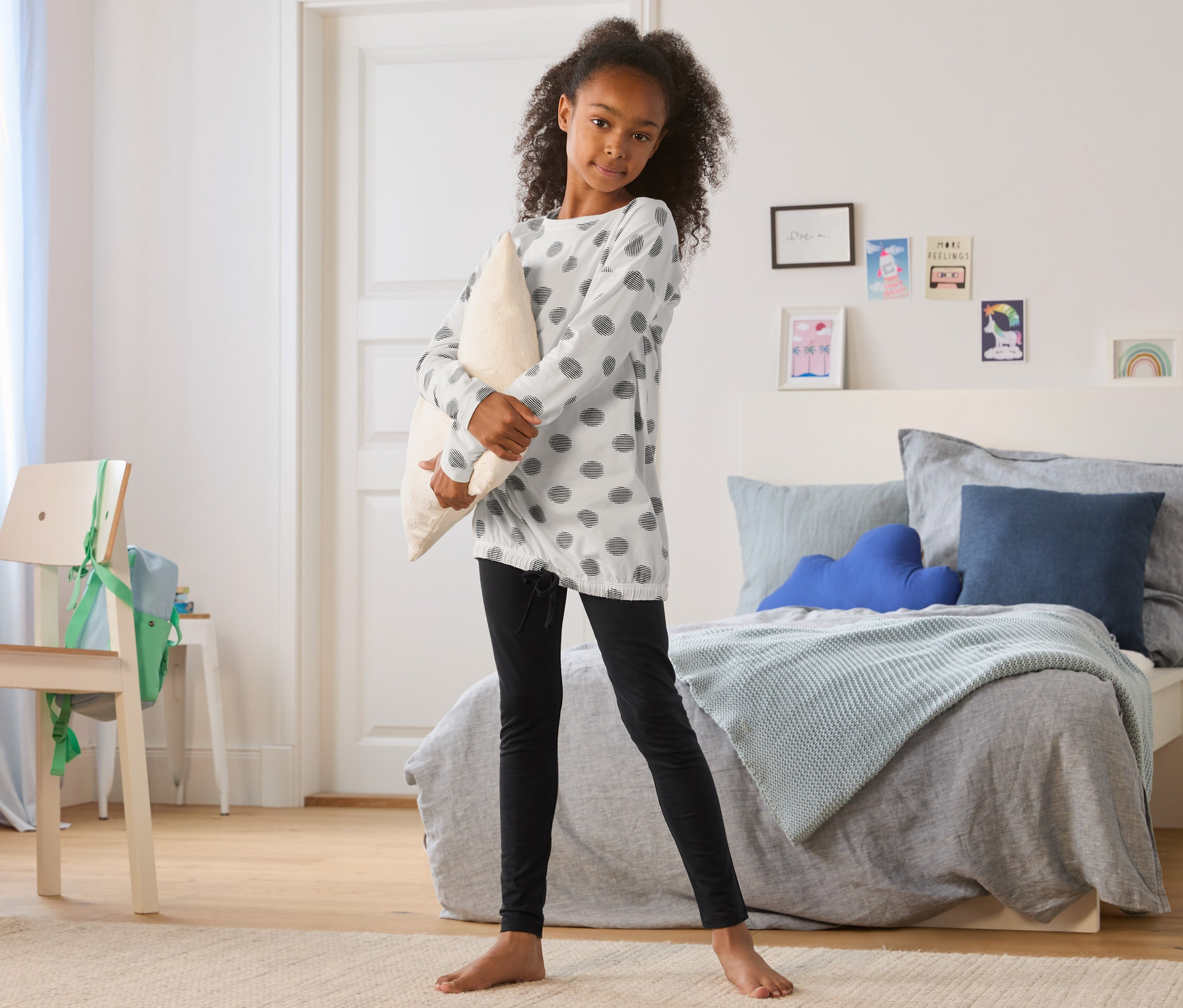 Dívka drží polštář, má na sobě černo-bílé dívčí pyžamo.