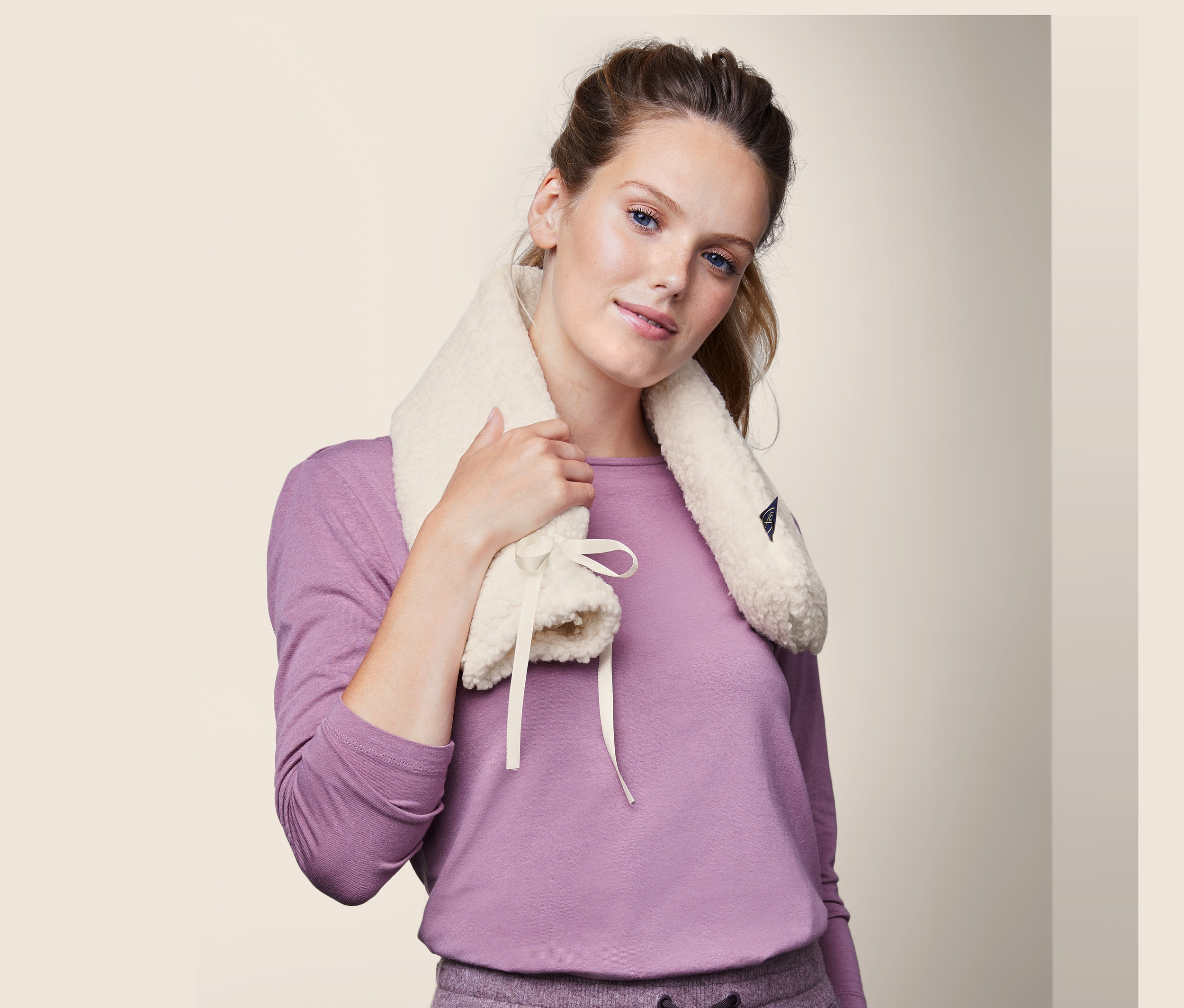 Žena si drží kolem krku podlouhlý termofor.