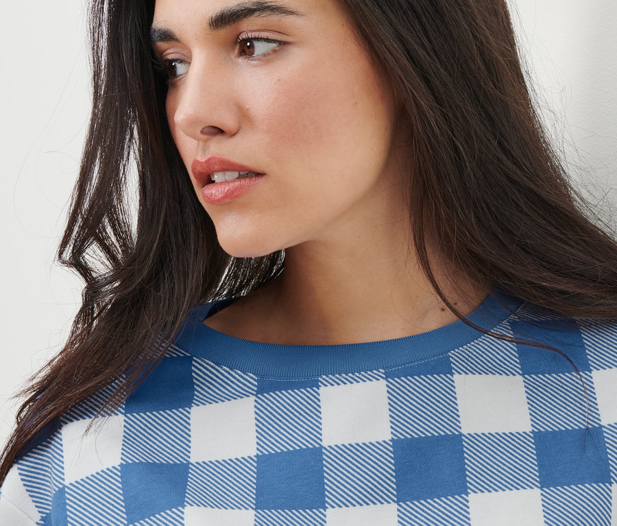 Detail mladé ženy s dlouhými hnědými vlasy a kostkované mikiny.