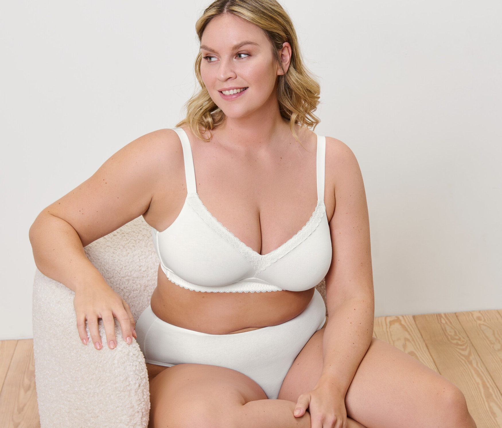 Žena sedí v křesle a má na sobě měkkou podprsenku.