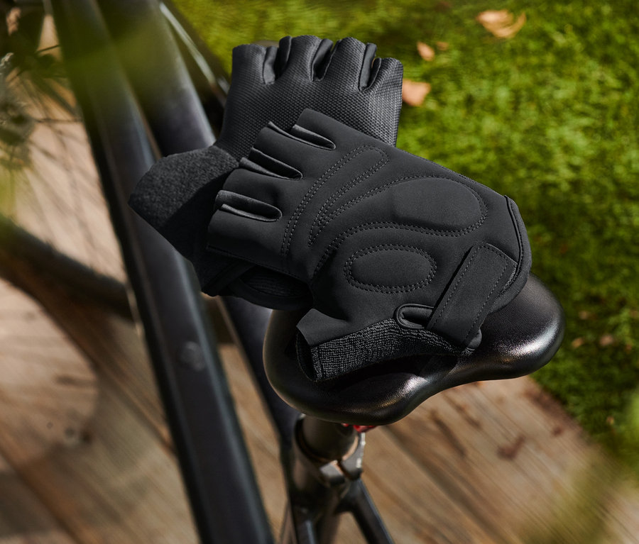 Černé cyklistické rukavice leží na sedle kola.