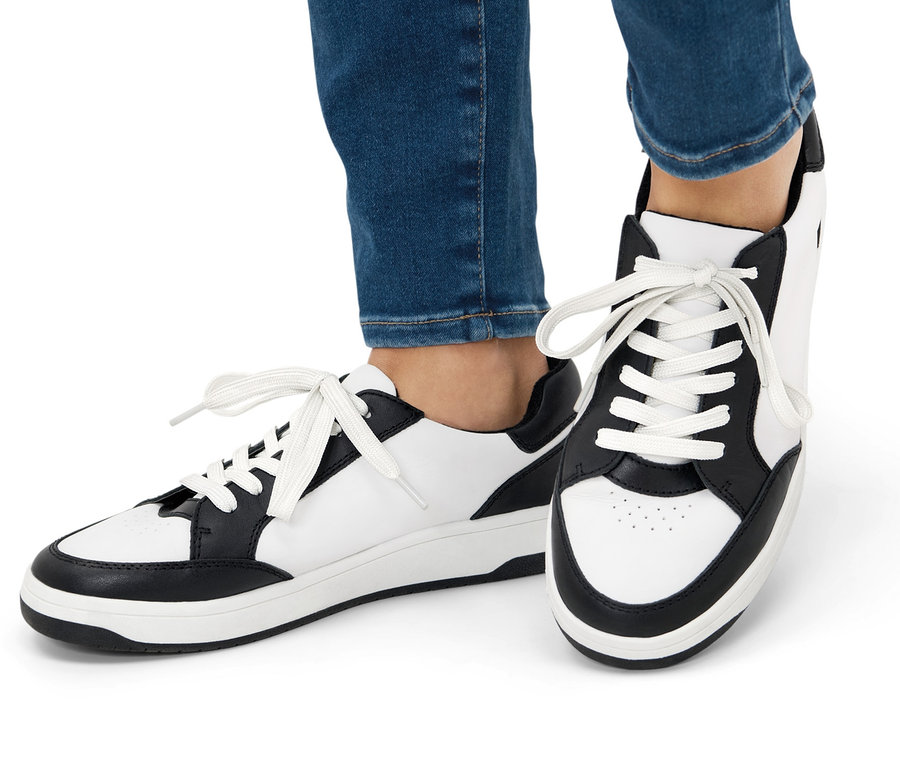 Nohy v džínových kalhotách a kožených teniskách.