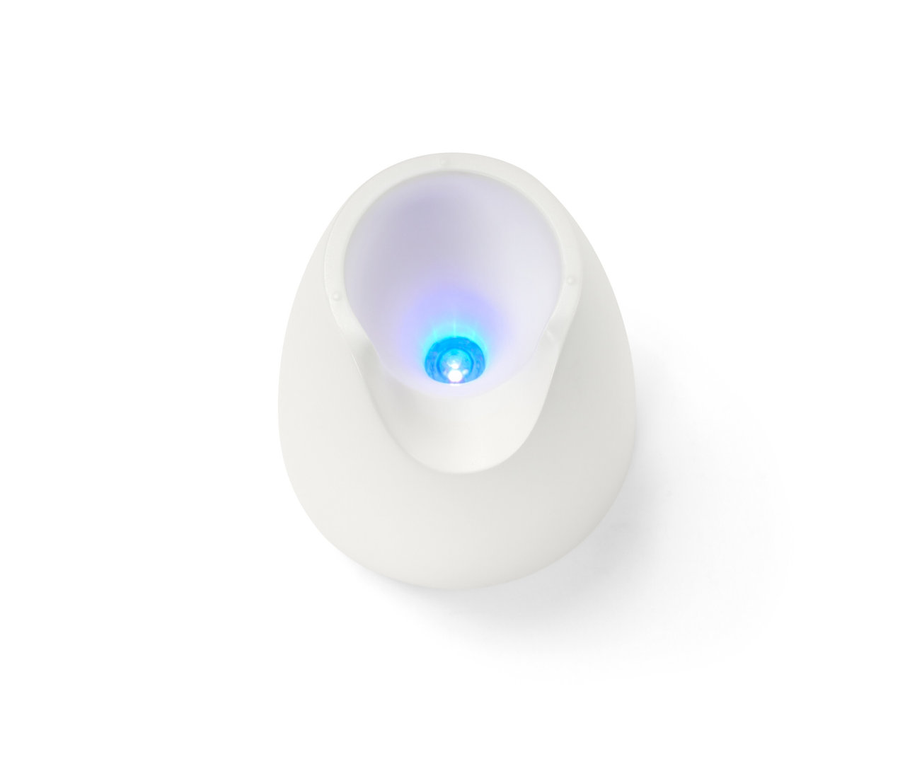 Detailní pohled shora na bílou UV lampu ze sady na manikúru a pedikúru 5 v 1, svítící modře.