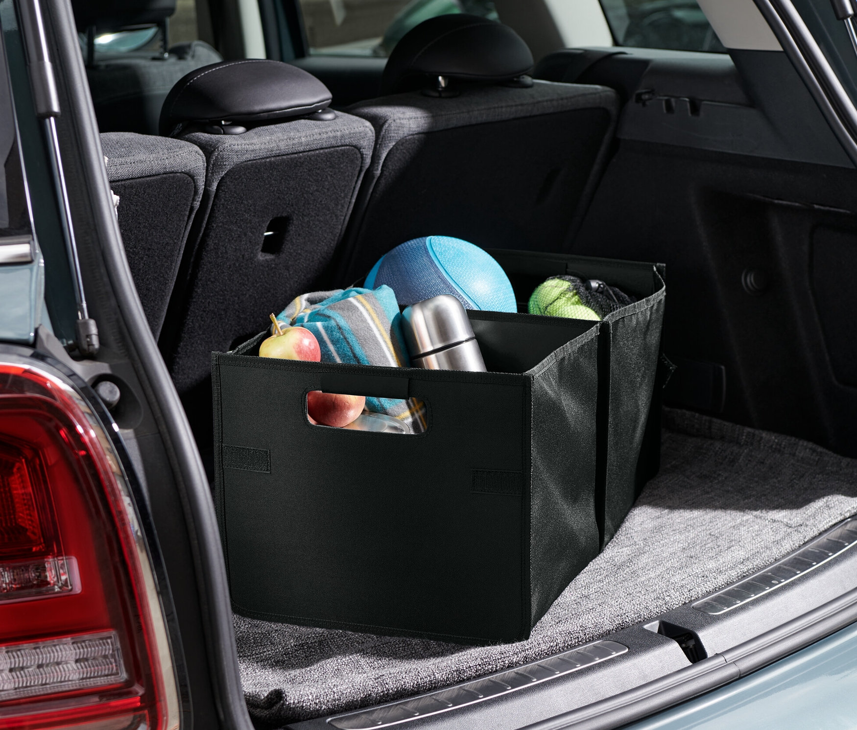 Skládací box do auta v kufru auta, uvnitř boxu je ovoce, deka, termoska a míče.