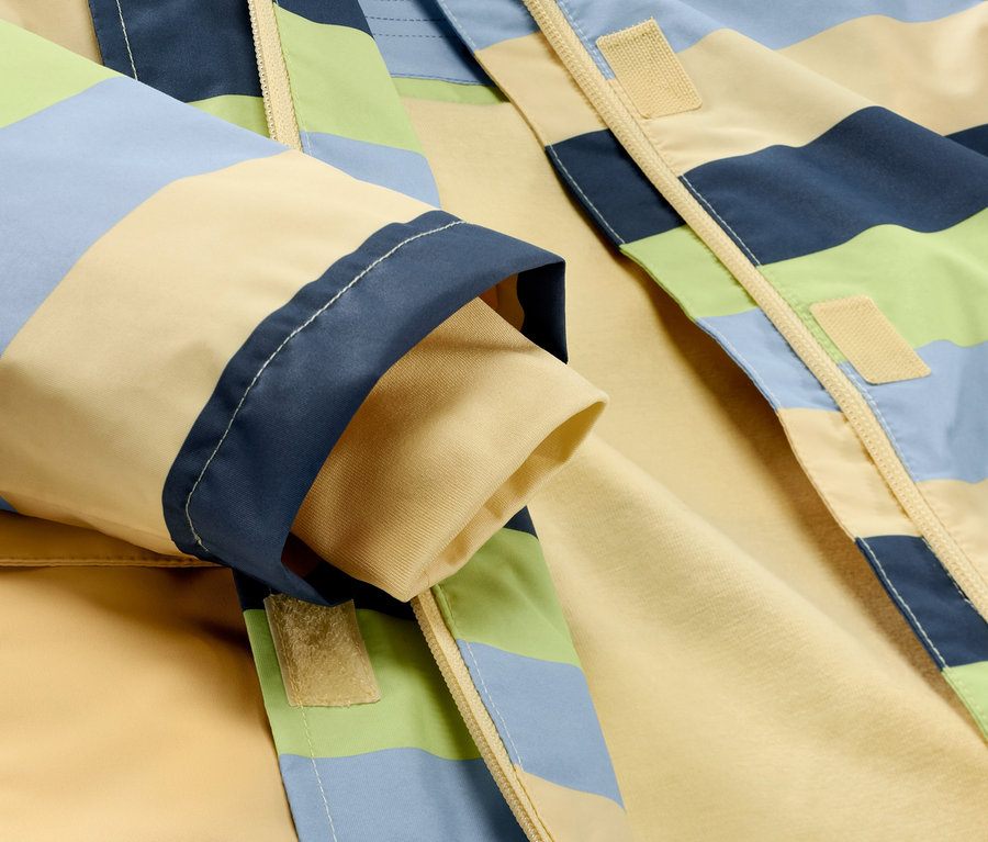 Detail dětské bundy do deště s proužky.