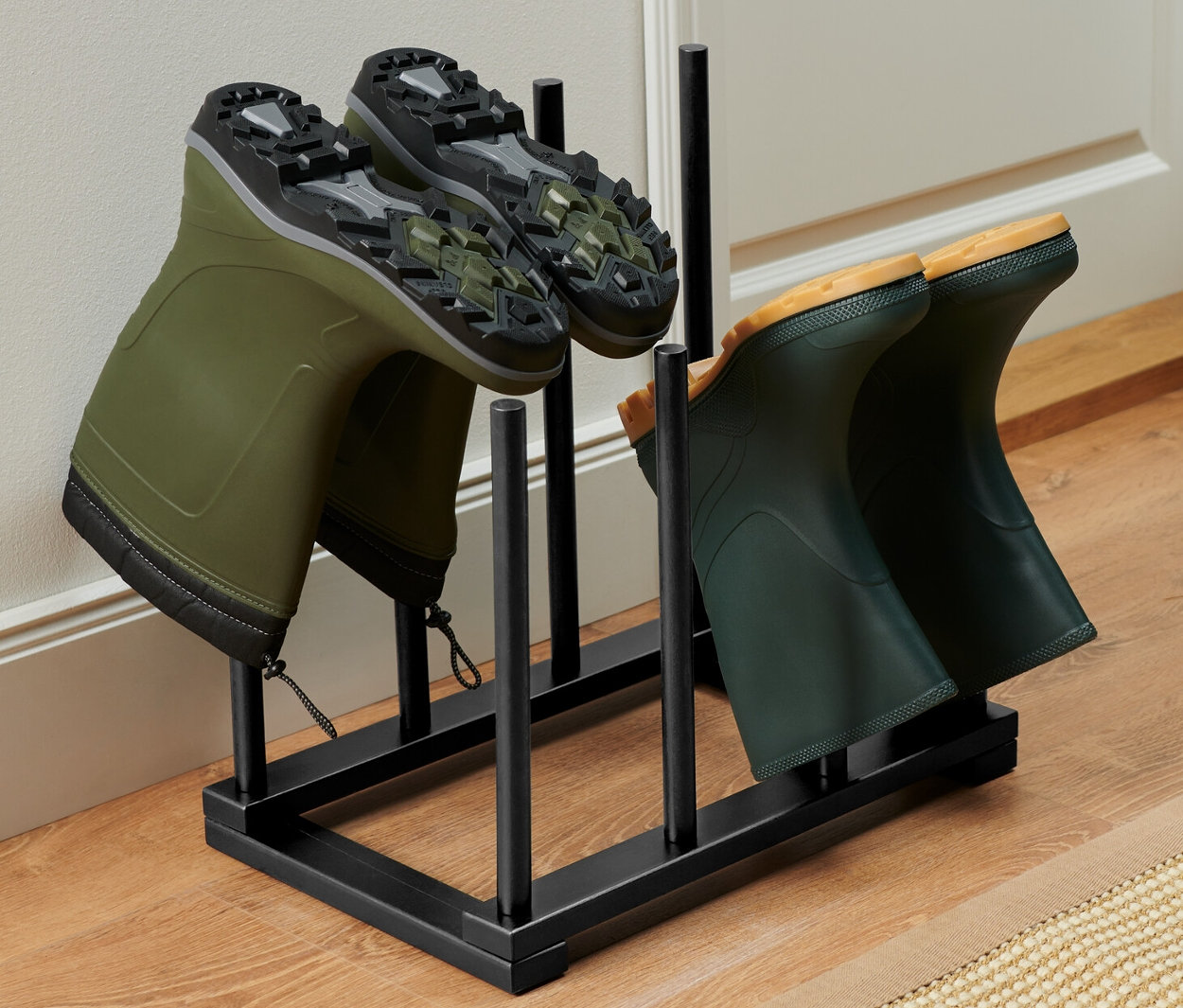 Dva páry zelených holínek ve stojanu na vysoké boty.