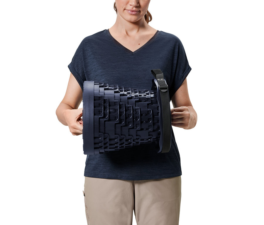 Žena drží teleskopickou kempingovou stoličku.